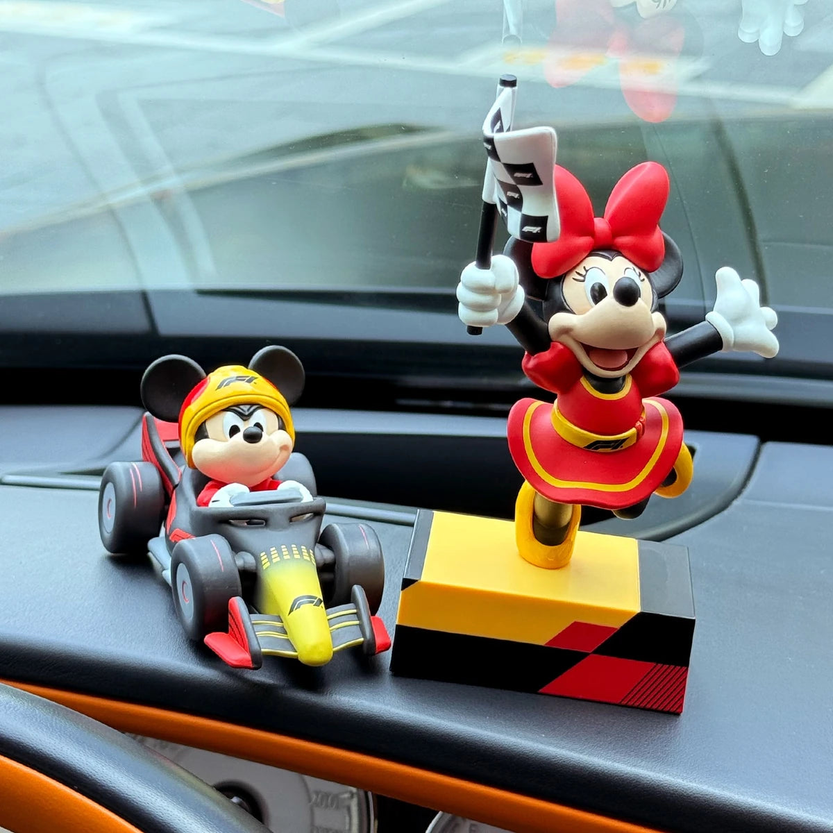Mickey race-car and Minnie finish-flag figures displayed on a car dashboard