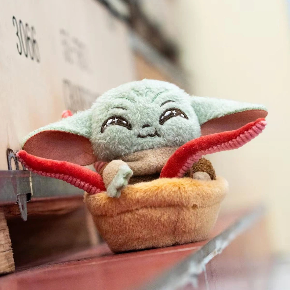 Smiling Grogu plush in a tentacle-filled basket beside a restaurant drink
