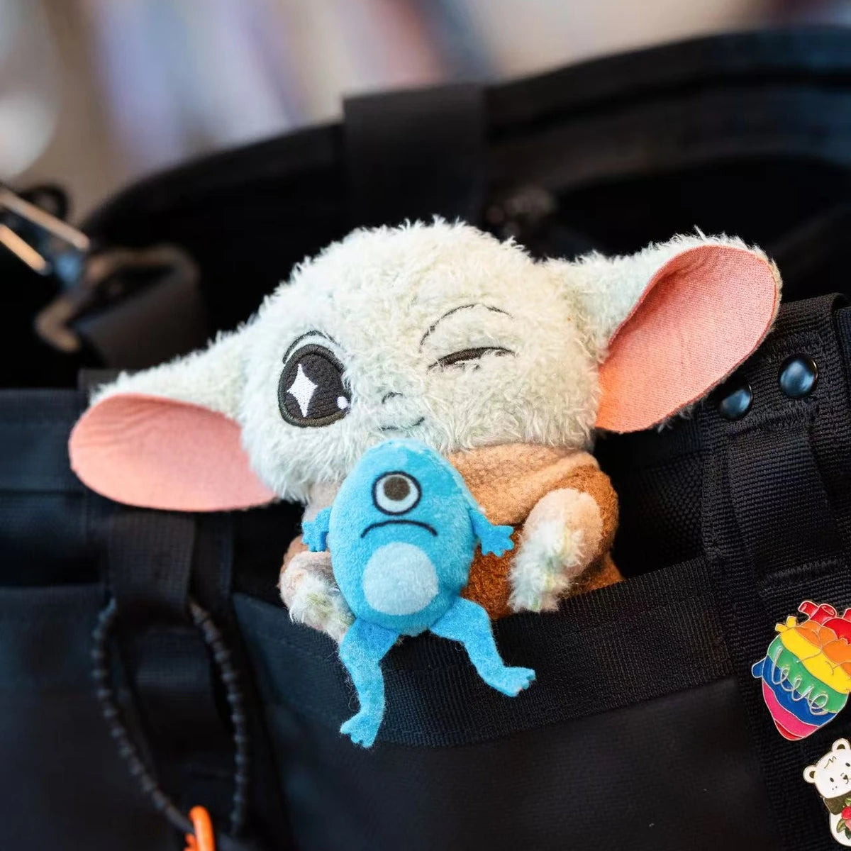 Grogu frog-creature plush keychain clipped to a black backpack