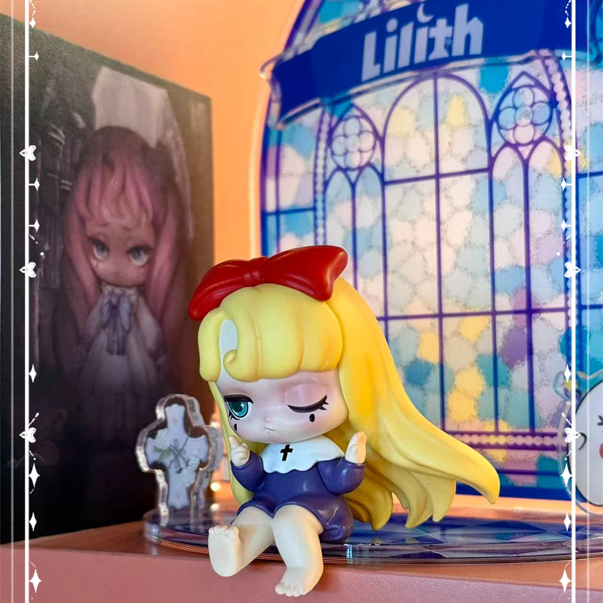 Blonde Lilith in a purple dress seated before a stained-glass Lilith display