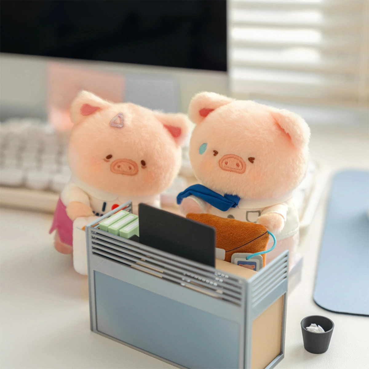 Two LuLu Piggy Office plush keychains peeking over a desk organizer, workplace blind box