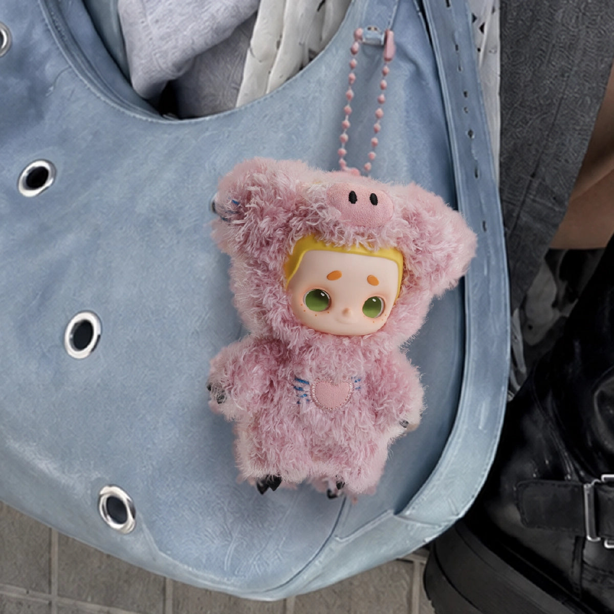 NOOK plush in a pink pig costume clipped to a light-blue tote bag