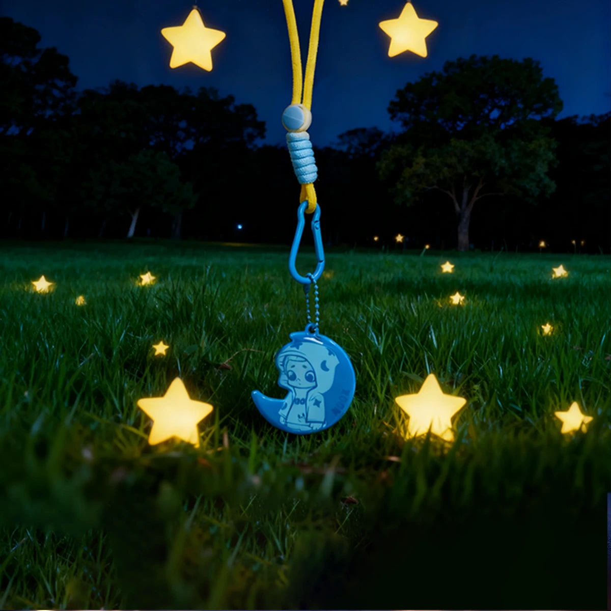 Blue Moon reflective crescent pendant glowing on a yellow strap in a starry field, NOOK Night Series