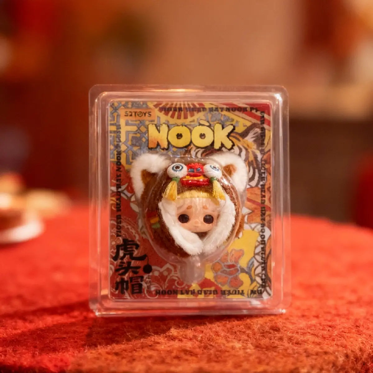 NOOK tiger-head hat plush charm shown through the front of its clear clamshell package