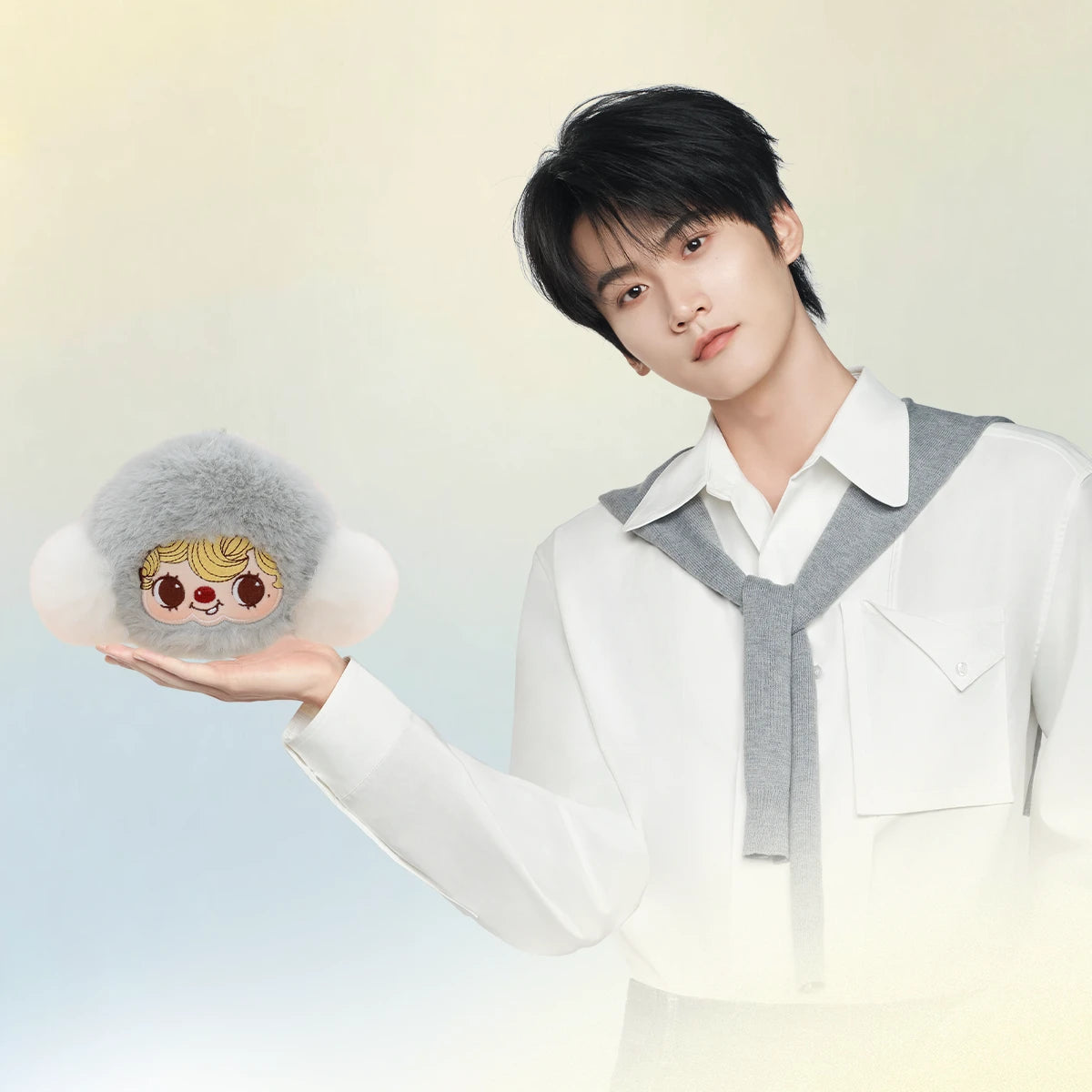 Model holding the fluffy grey POUKAPOUKA Pocket Cosmos earphone case in palm, plush keychain