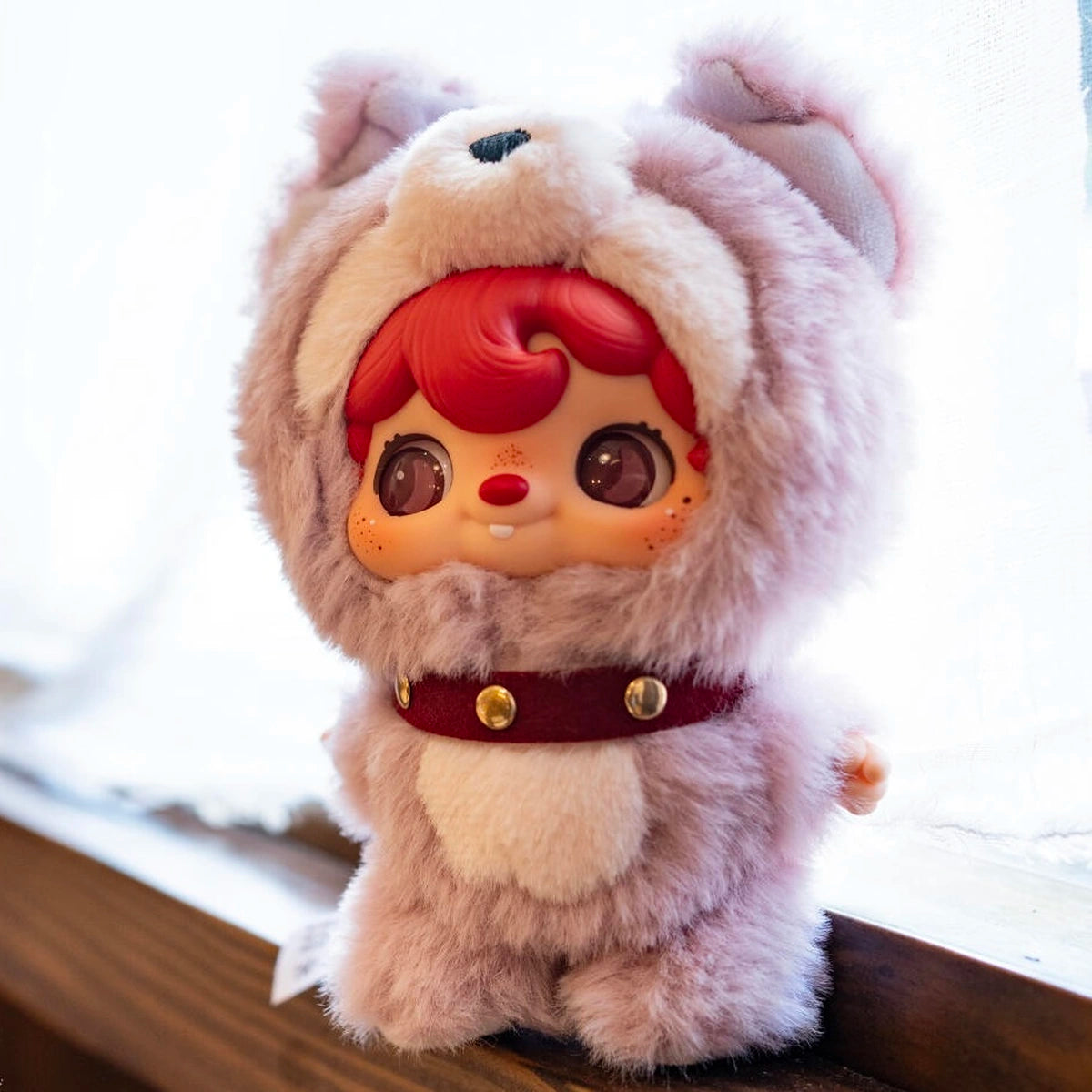 POUKAPOUKA in a lavender Tom costume with red hair on a snowy windowsill