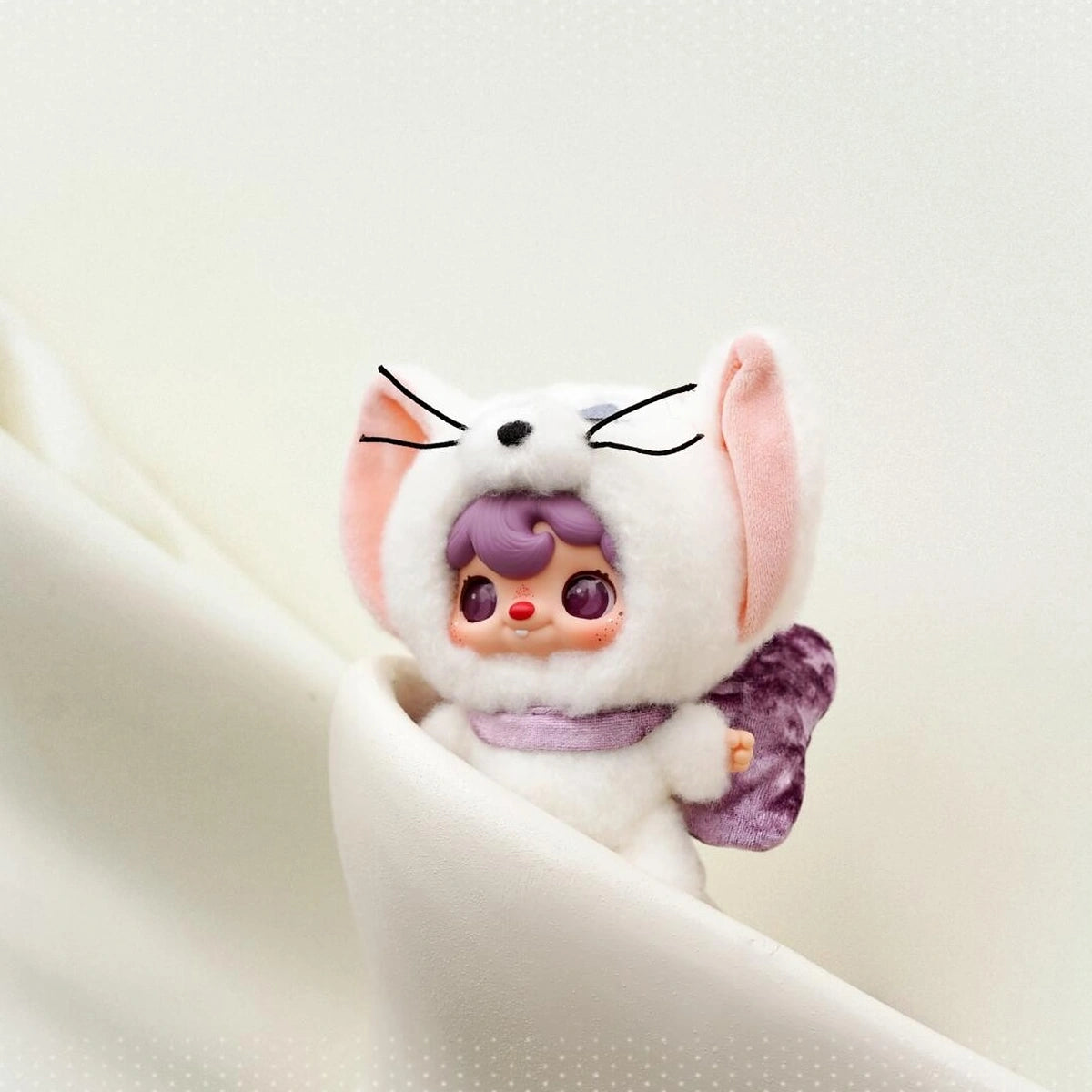POUKAPOUKA white Tom costume nestled in folds of white fabric
