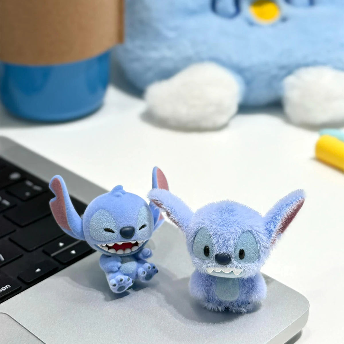 大きなぬいぐるみ玩具の横に2台のステッチミニメ フィギュアがラップトップに立っている