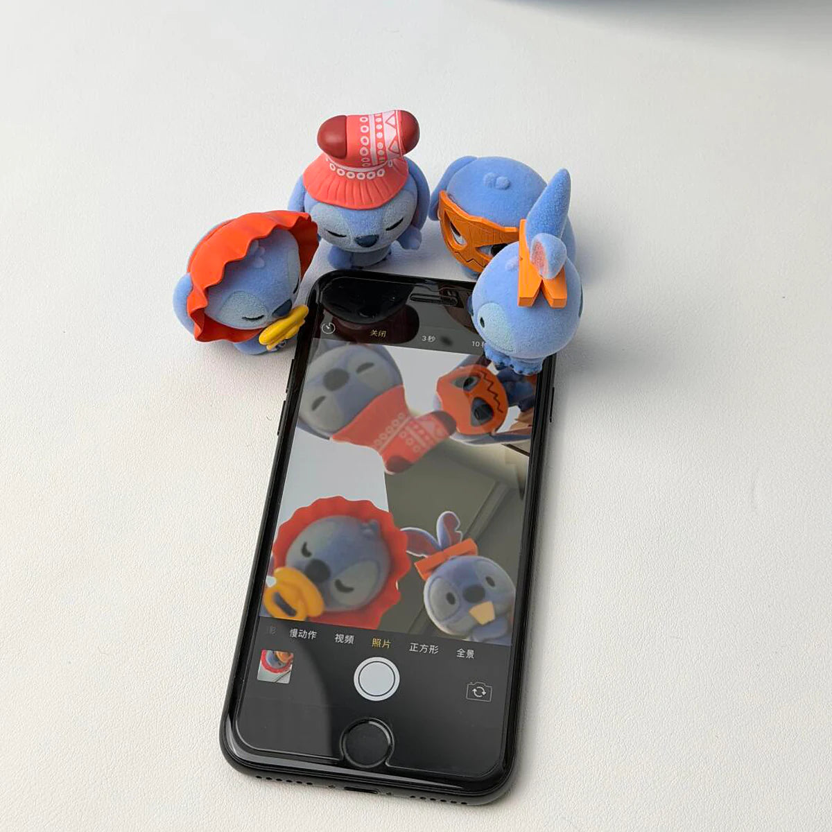 3人のステッチミニメ フィギュアがグループ写真を見せている電話を ポーズしている