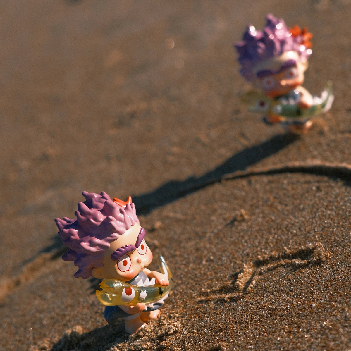 Two purple-haired CiCiLu sea-creature figures walking together on a sandy beach