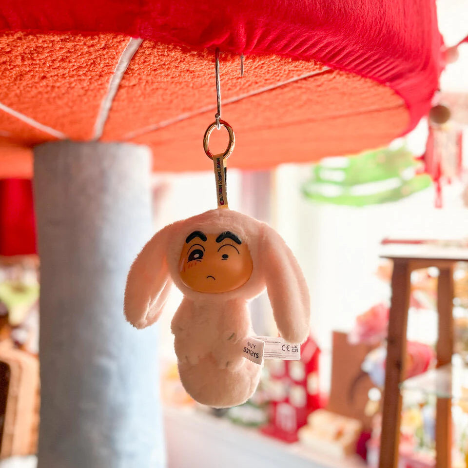 Pink rabbit-costume Shinchan Big Tails plush keychain hanging beneath a red canopy