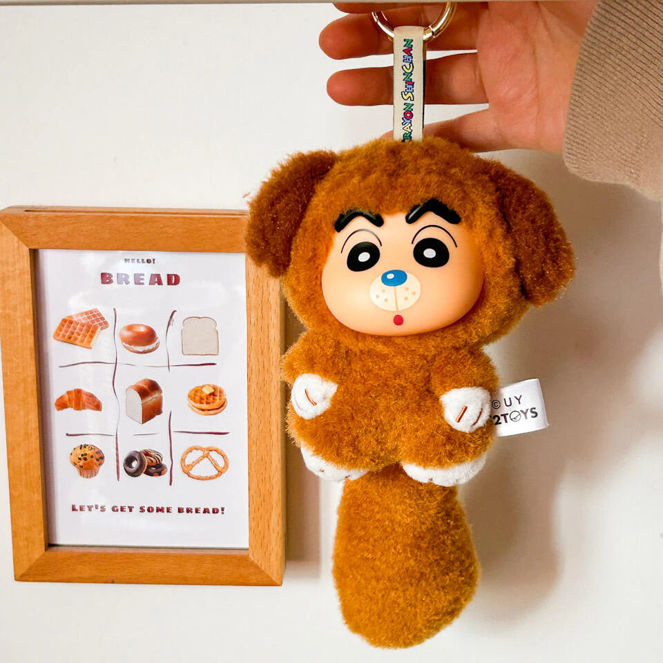 Brown dog-costume Shinchan Big Tails plush keychain held beside framed bread artwork