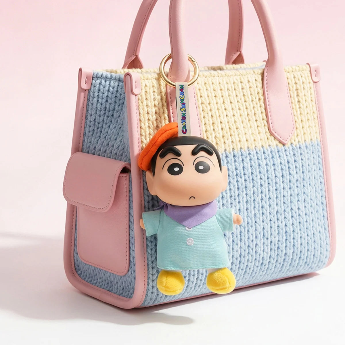 Shinchan artist-outfit plush keychain hanging from a blue and cream handbag