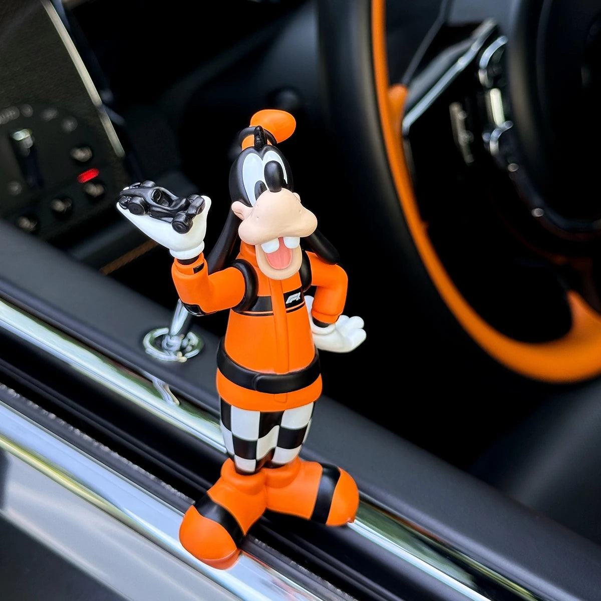 Goofy pit-crew figure displayed inside an orange-accented car