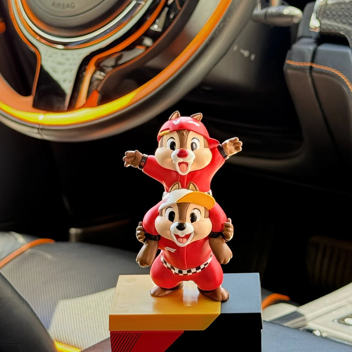 Chip and Dale F1 team figure displayed beside a car steering wheel