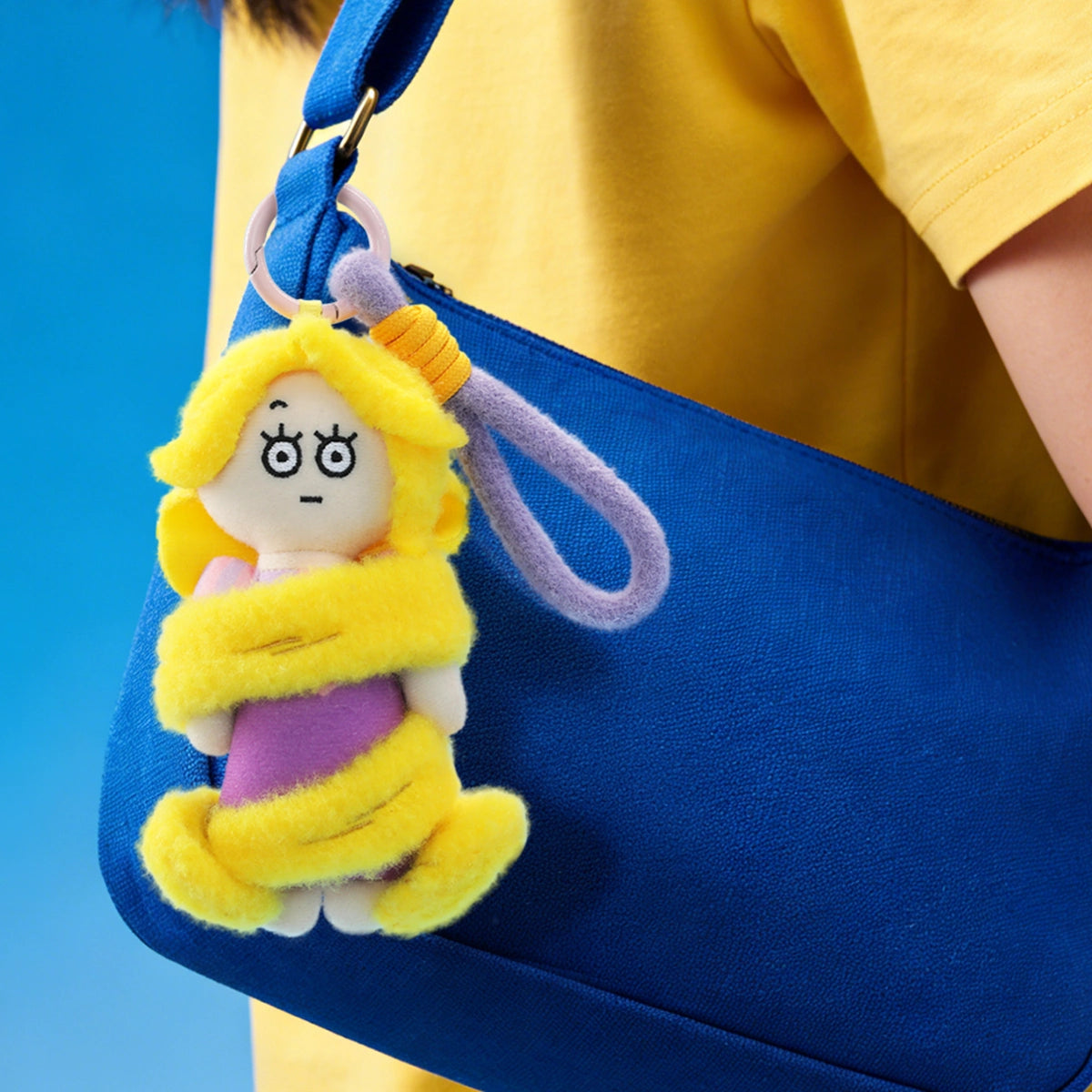 Rapunzel plush keychain clipped to a blue shoulder bag as a cute accessory, Disney Princess On The Run