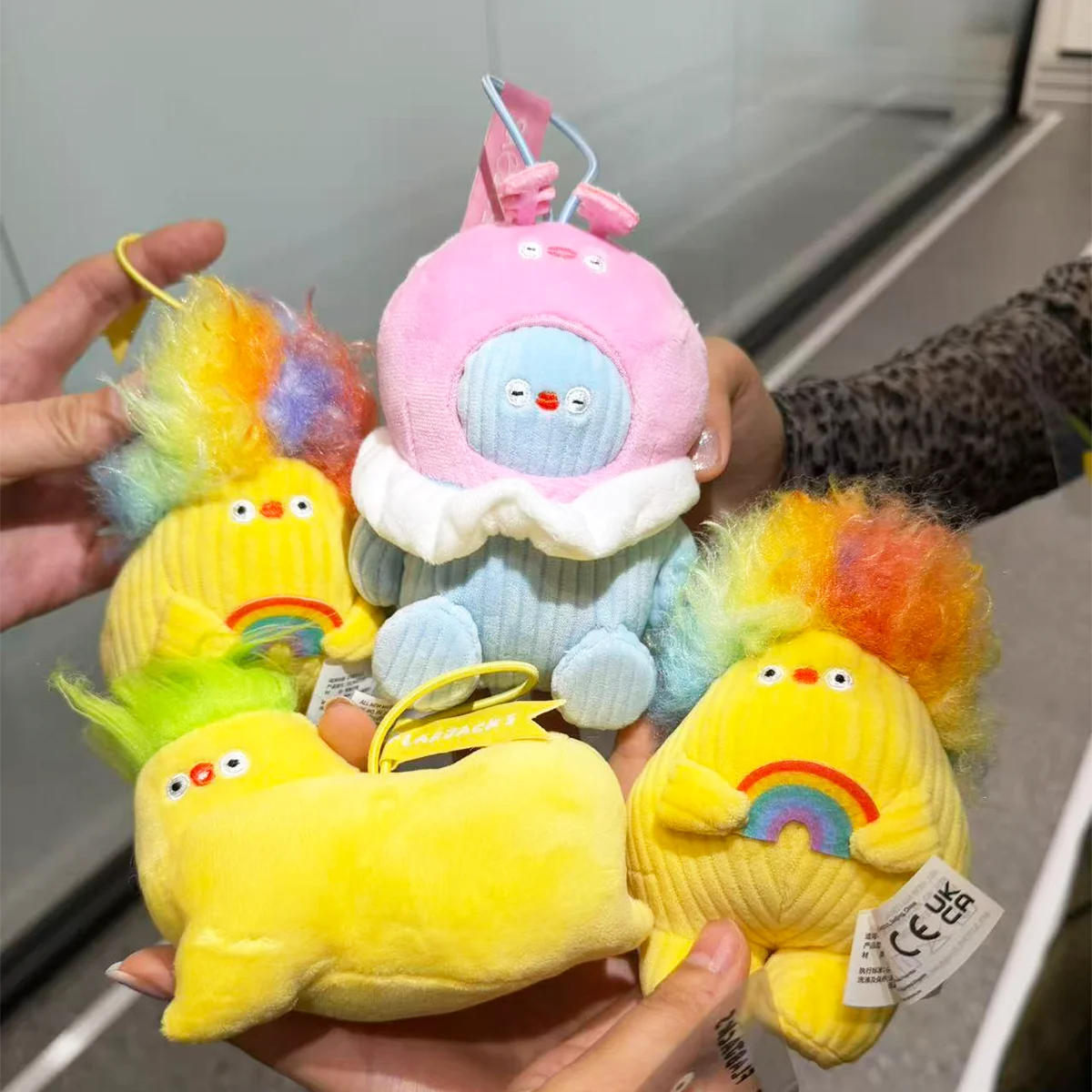 Hands holding four Flabjacks plush charms including Joy, Peaceful, Funky, and Loopy
