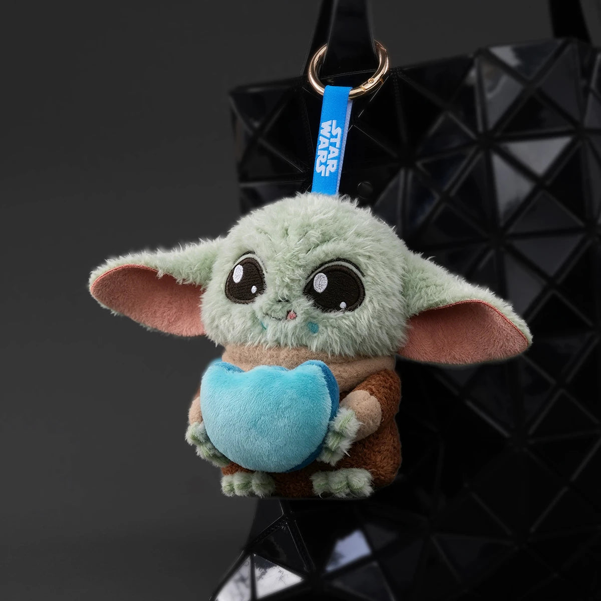 Grogu blue-heart plush keychain hanging from a black bag by a Star Wars strap