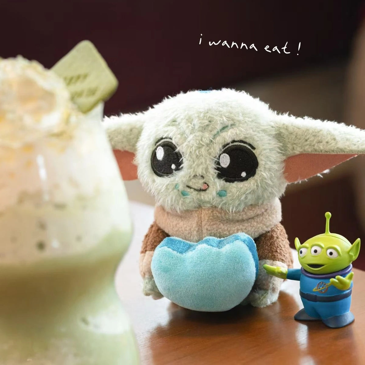 Grogu blue-heart plush beside a Toy Story Alien figure and dessert drink