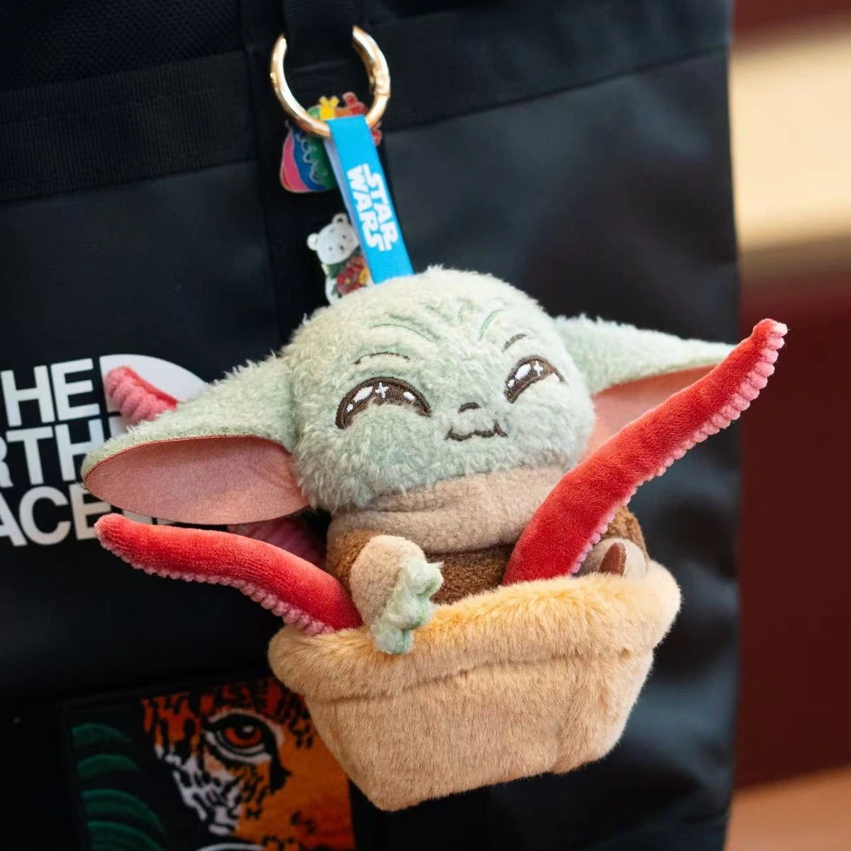 Grogu tentacle-basket plush keychain attached to a black backpack