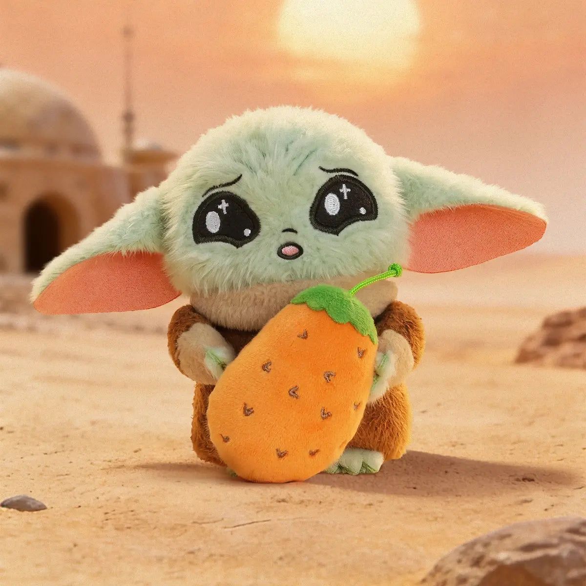 Grogu plush holding an oversized orange carrot in a desert at sunset
