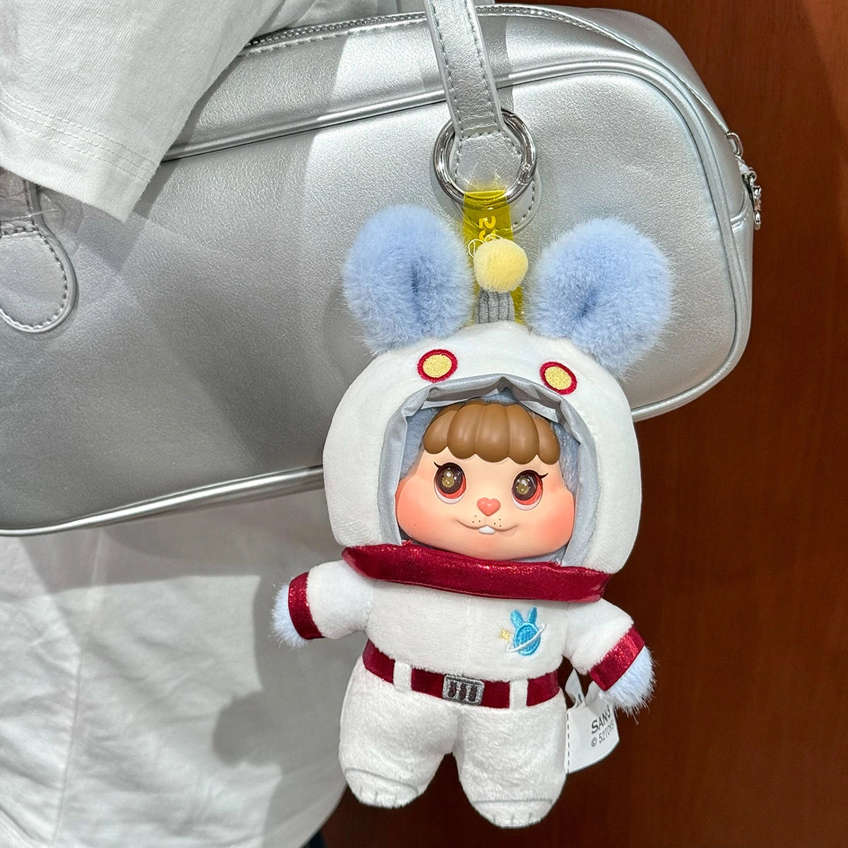Little Buns white rabbit astronaut plush keychain attached to a silver handbag