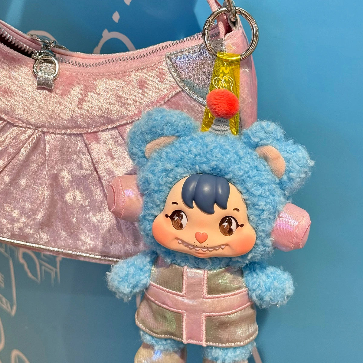Little Buns blue bear space-suit plush keychain attached to a pink handbag