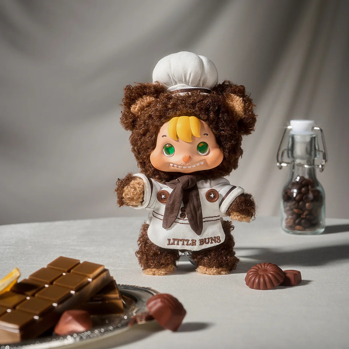 LITTLE BUNS chocolate chef doll in bear hood and white chef coat beside chocolates, Melting Together series