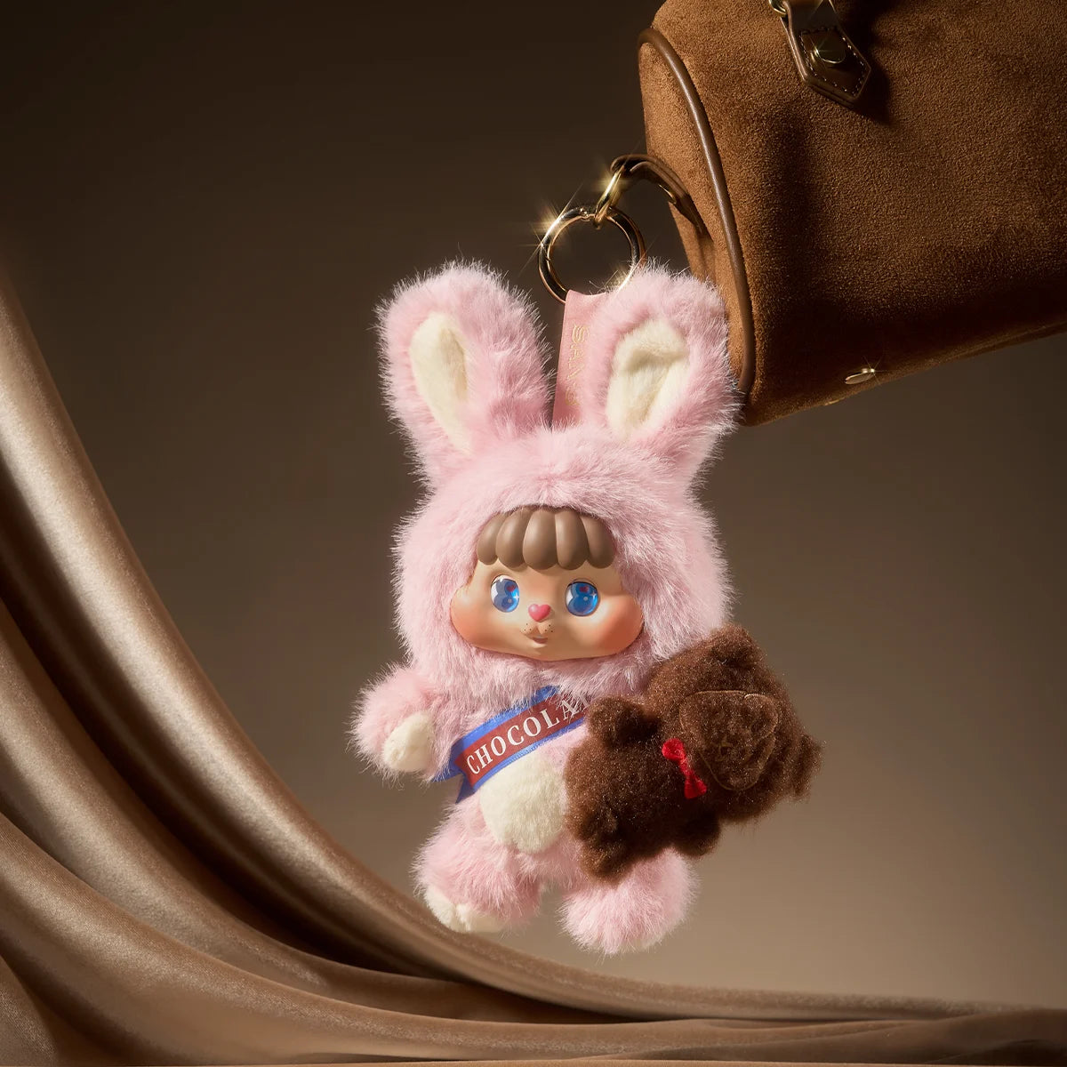 Pink Bunny Bing charm with CHOCOLAT sash hanging from a suede bag, Little Buns Melting Together