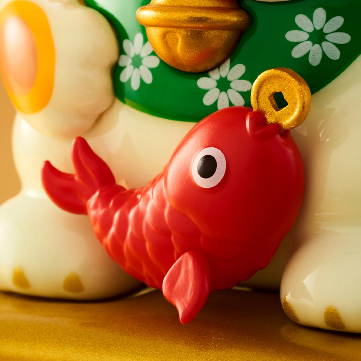 Close-up of the red koi fish charm and gold bell on LuLu the Piggy lucky-cat pig figures