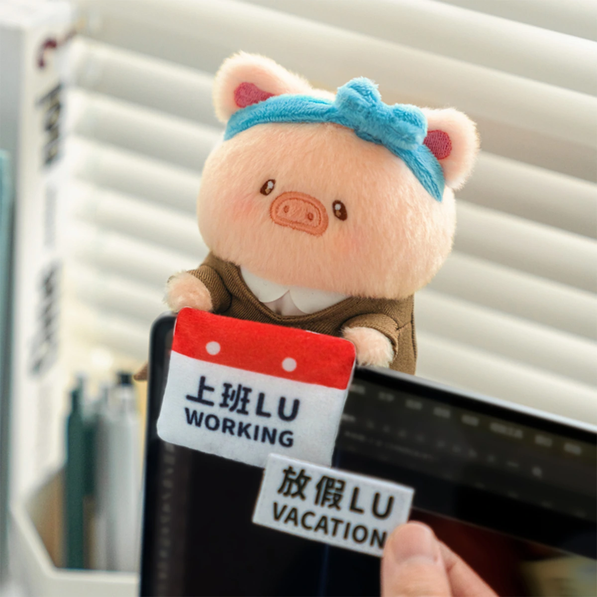 Recharge Lu piggy plush keychain with blue bow on a tablet with Working and Vacation tags, LuLu Piggy Office