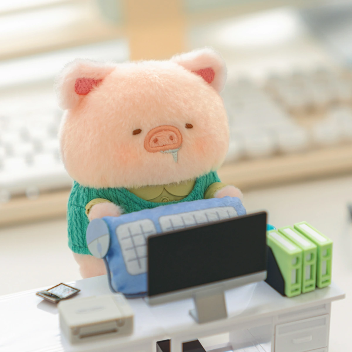 Super Tired Lu piggy plush keychain in green sweater hugging a keyboard at a desk, LuLu Piggy Office