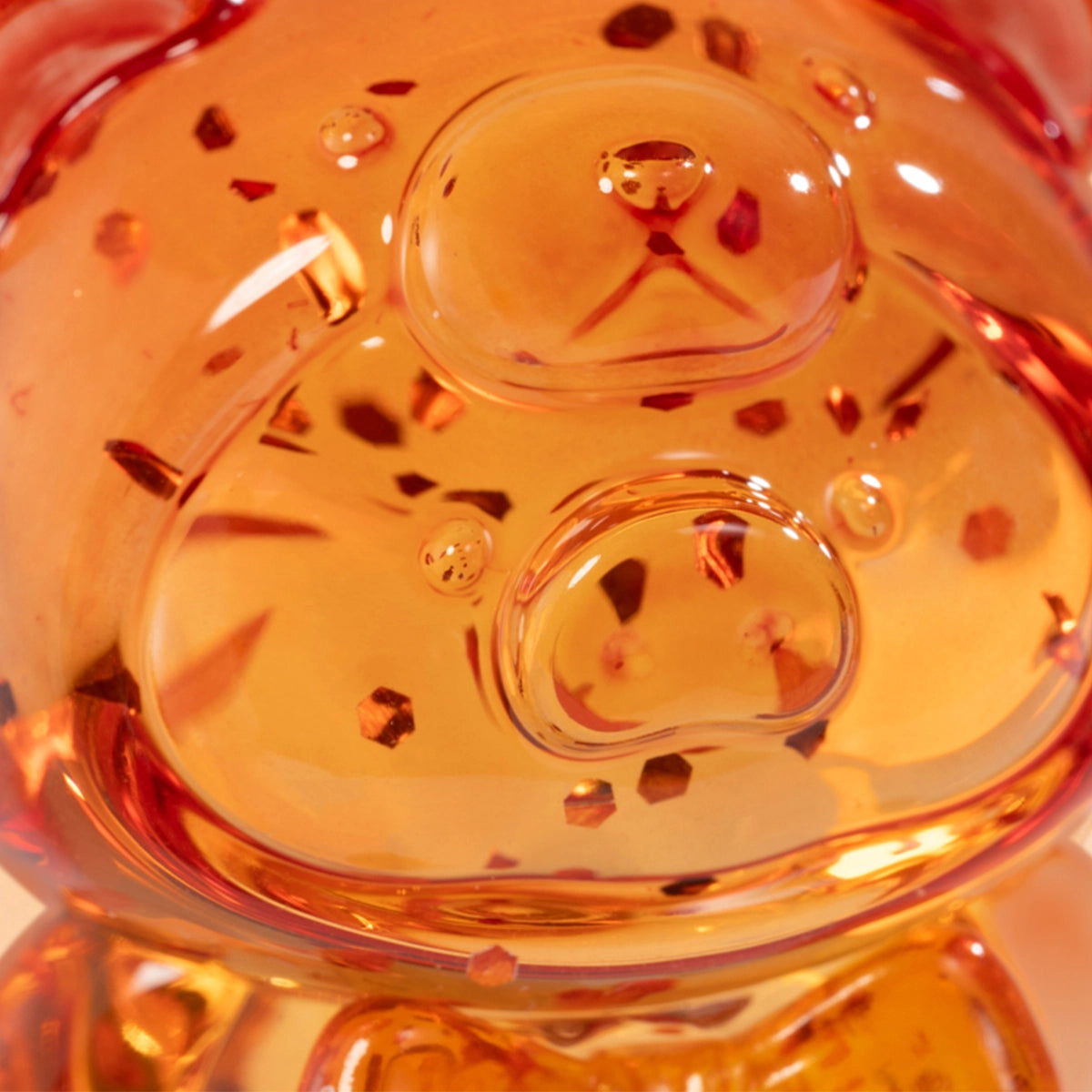 Close-up of an amber translucent Lulu piggy figure body with gold flecks, Teddy Mini Ore Collection