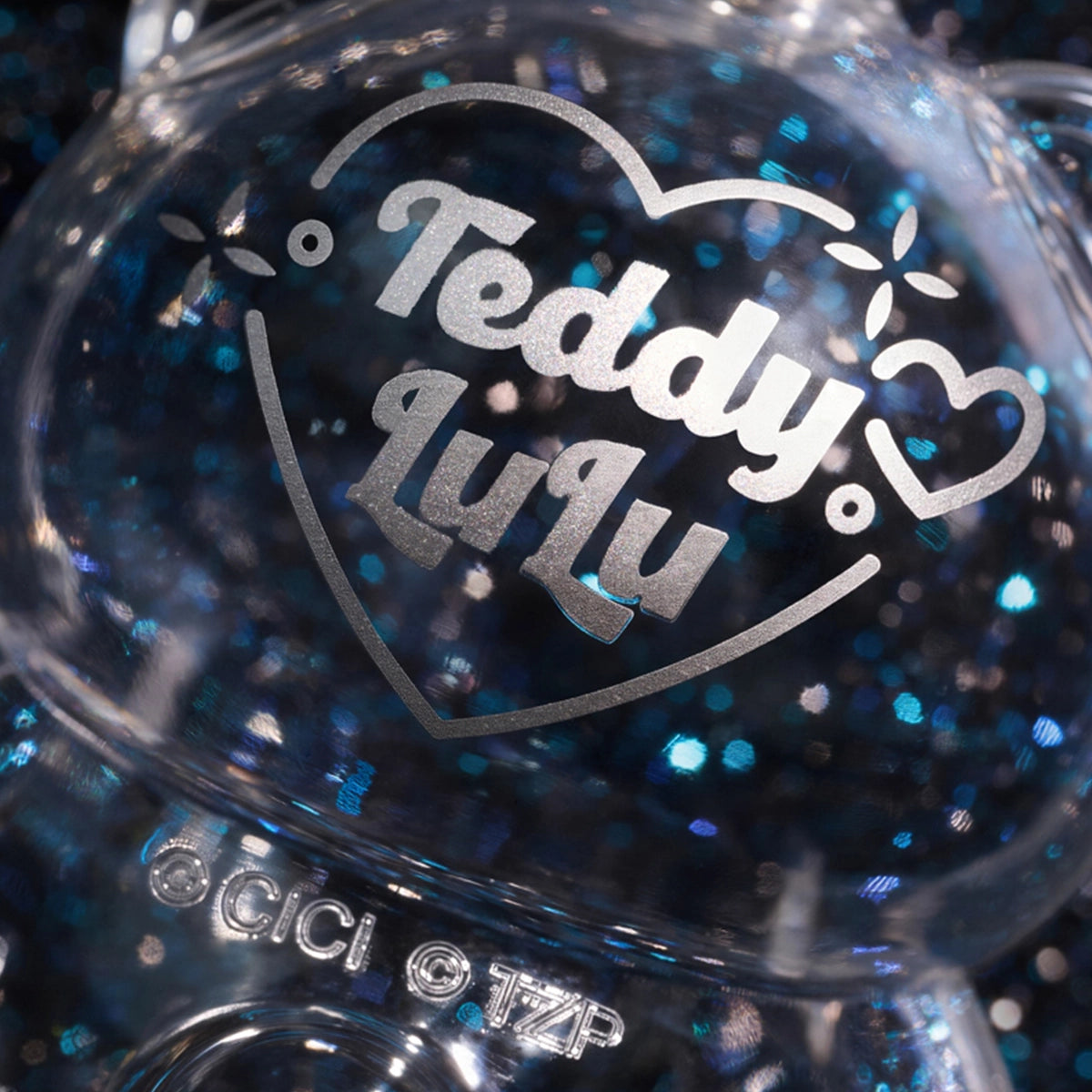 Close-up of a clear glittery Lulu piggy figure with Teddy Lulu heart logo, Ore Collection