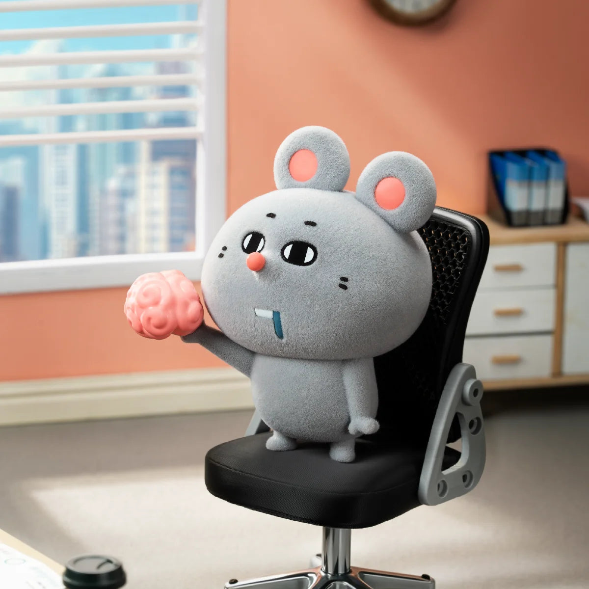 Meiji corporate mouse seated in an office chair and holding a pink brain-shaped object