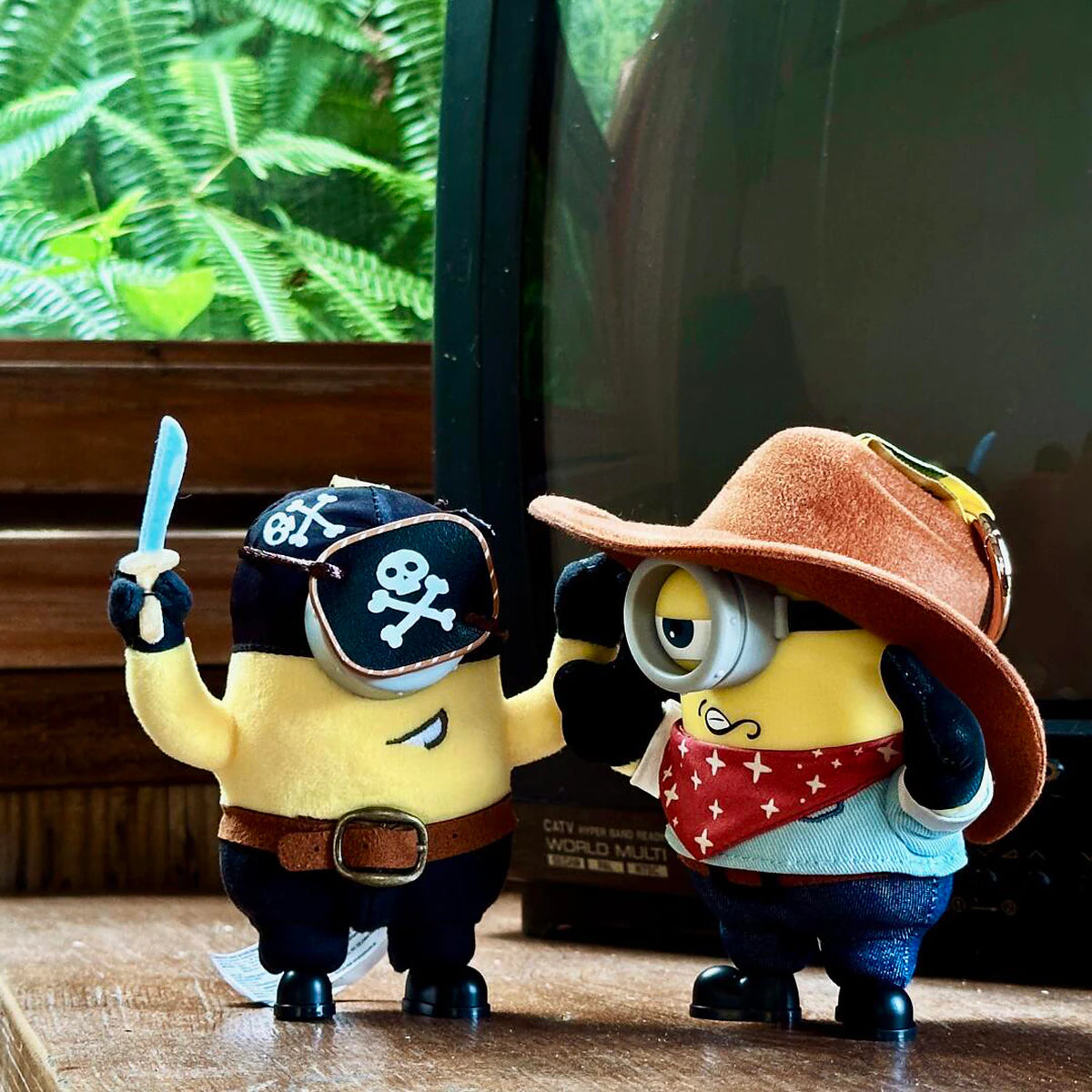Pirate Carl and Cowboy James Minion plush toys standing together in a rustic room