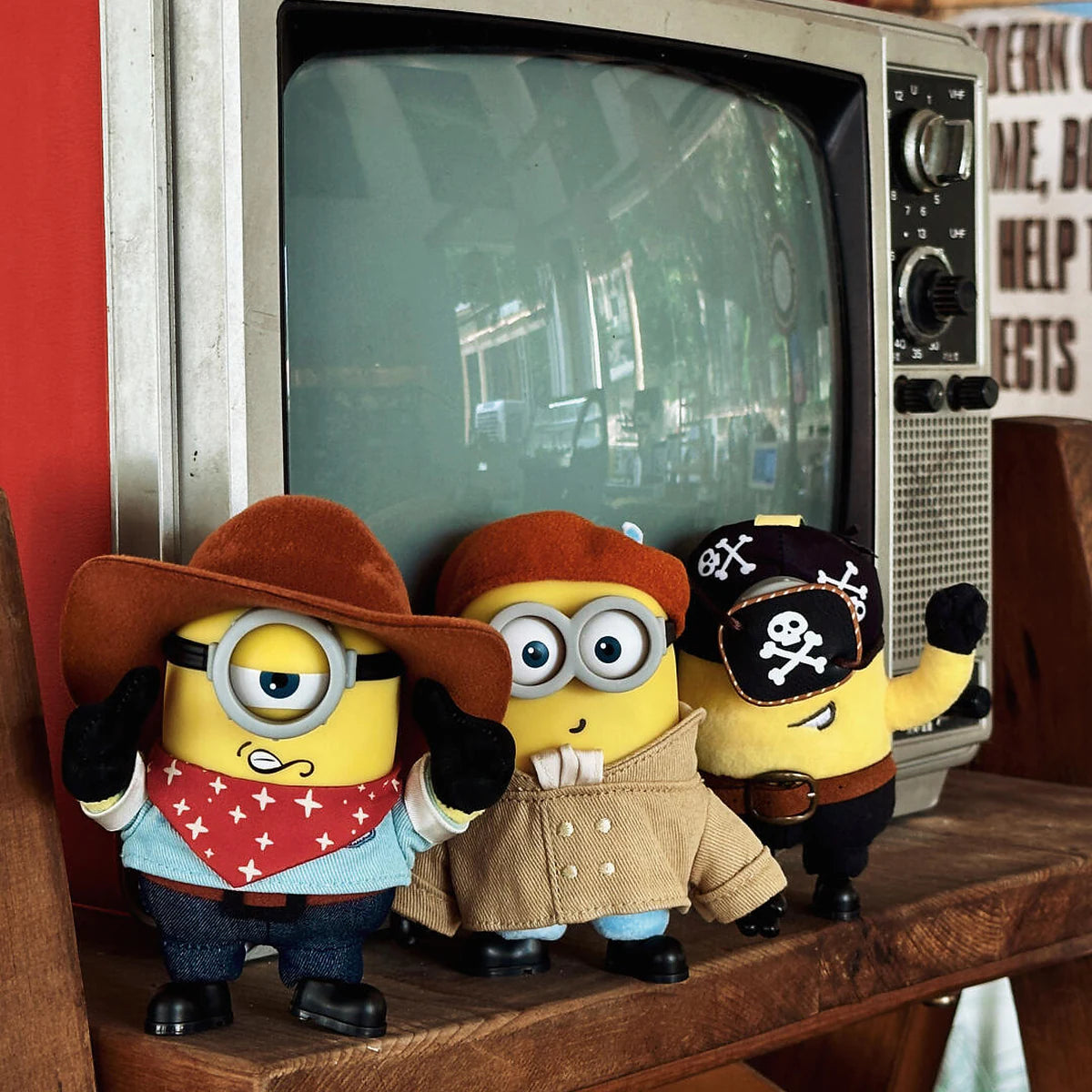 Cowboy James, Artist Henry, and Pirate Carl Minion plush toys displayed beside a vintage television