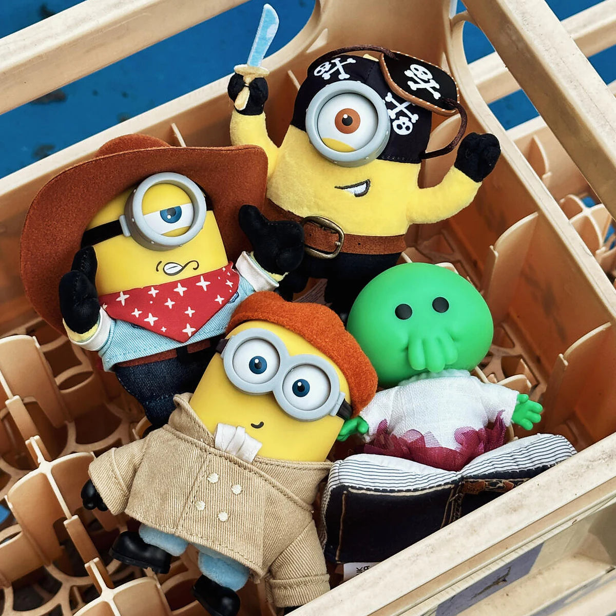 Cowboy James, Pirate Carl, Artist Henry, and Goomi plush toys inside a wooden crate