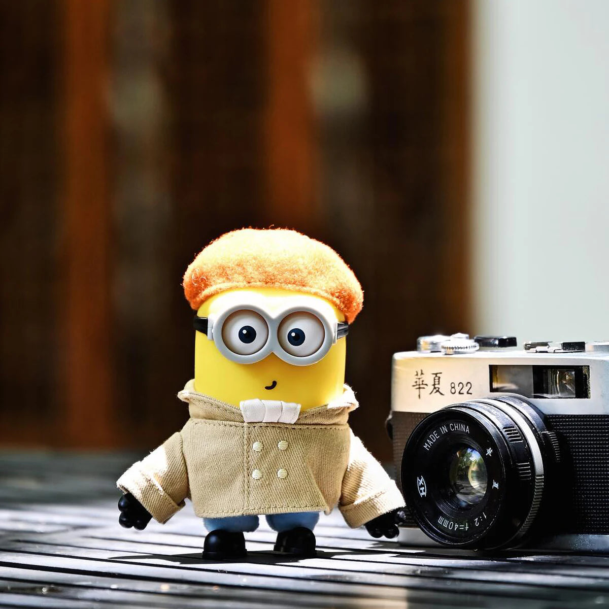 Artist Henry Minion plush standing beside a vintage camera