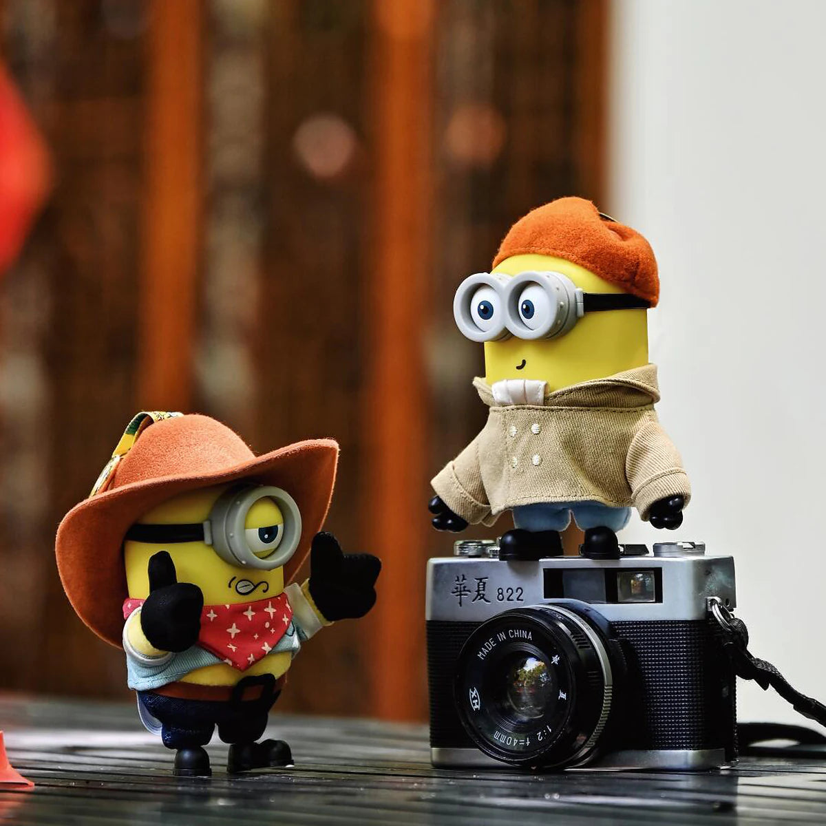 Cowboy James and Artist Henry Minion plush toys posing with a vintage camera