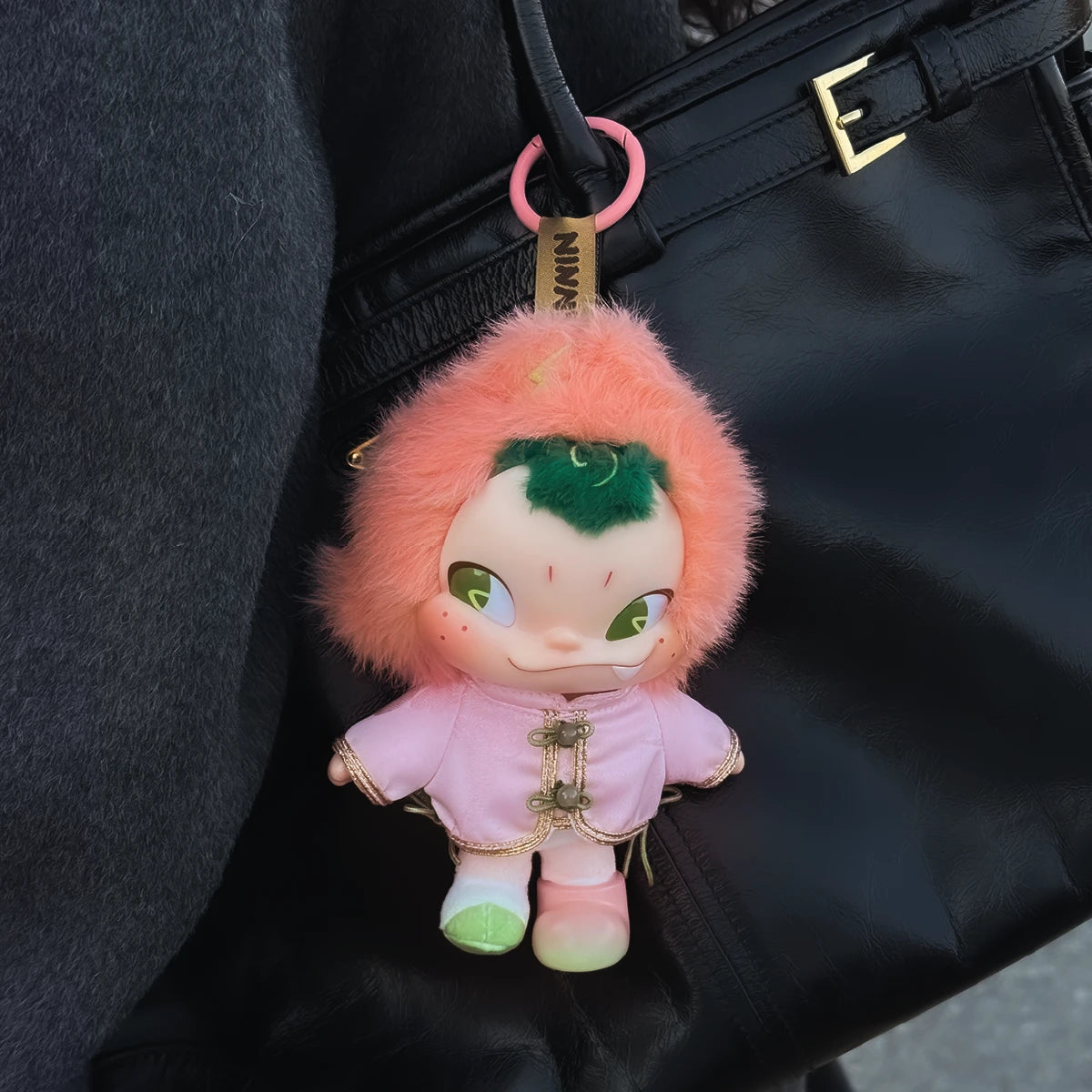 NINNIC Fairy Peach plush figure hanging from a black handbag by its pink ring