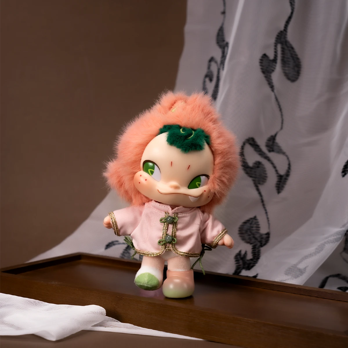 NINNIC Fairy Peach plush figure posed on a wooden ledge beside a patterned curtain