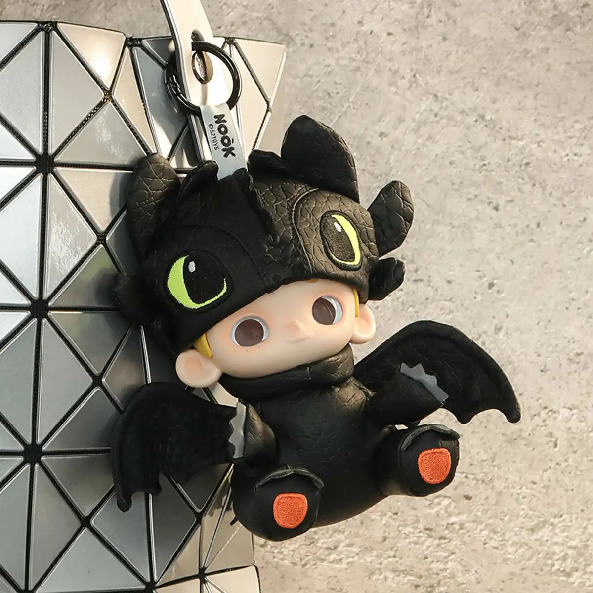 NOOK as Toothless keychain clipped to a geometric silver bag, NOOK x Toothless limited edition
