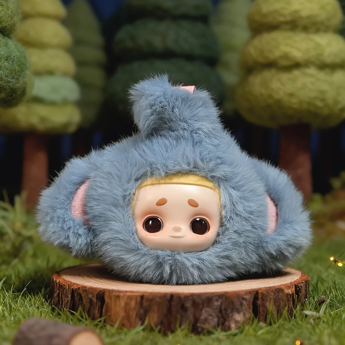 Curious Elephant Nook in a grey elephant hood with trunk and tusk on top, on a wood slice, My Date with the Forest