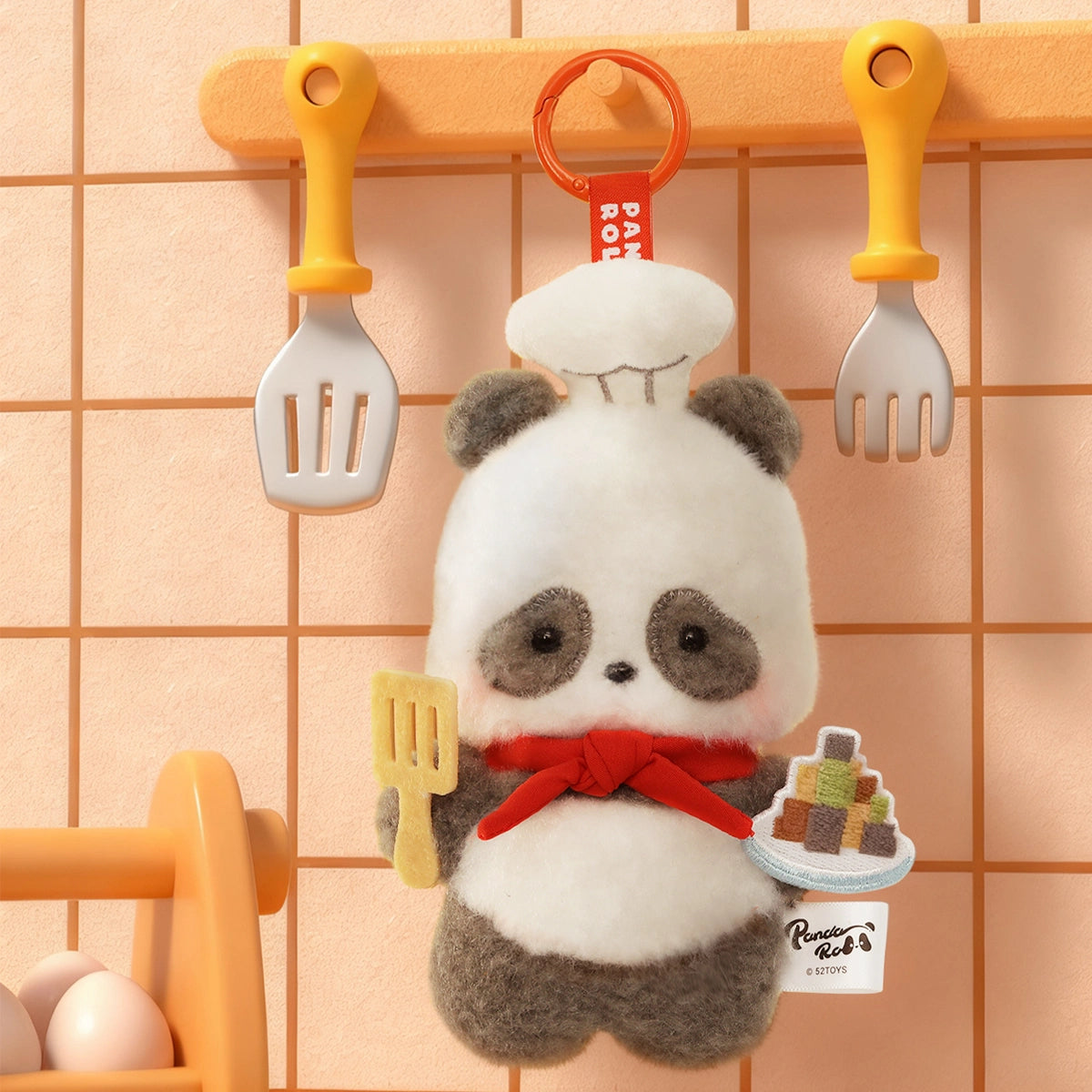 Panda Chef plush charm in white toque with spatula and macarons hung in a kitchen scene, Panda Roll