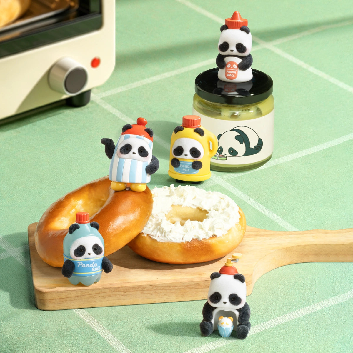 Panda Roll MiniMe figures arranged with bagels and a jar on a wooden cutting board