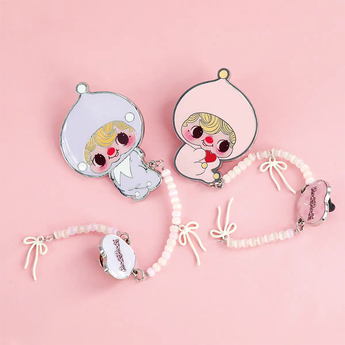 Pink and lilac POUKA enamel brooches with beaded bow straps displayed together, POUKAPOUKA brooch series