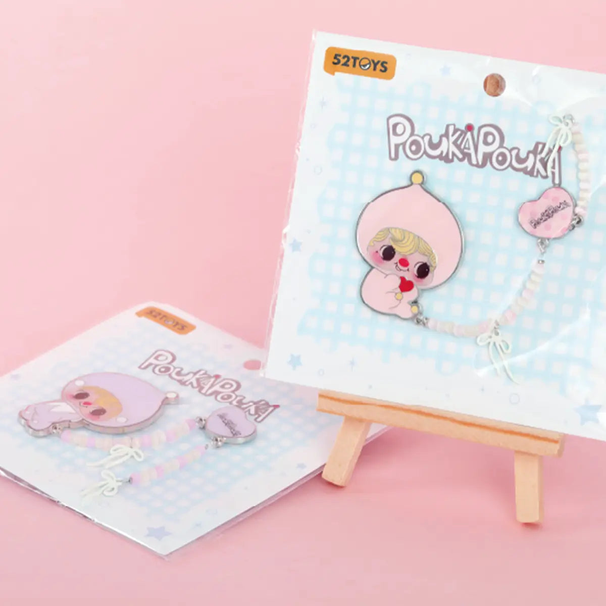POUKA Sweet Lilac and Blush Pink brooches in POUKAPOUKA blister packaging on a mini easel