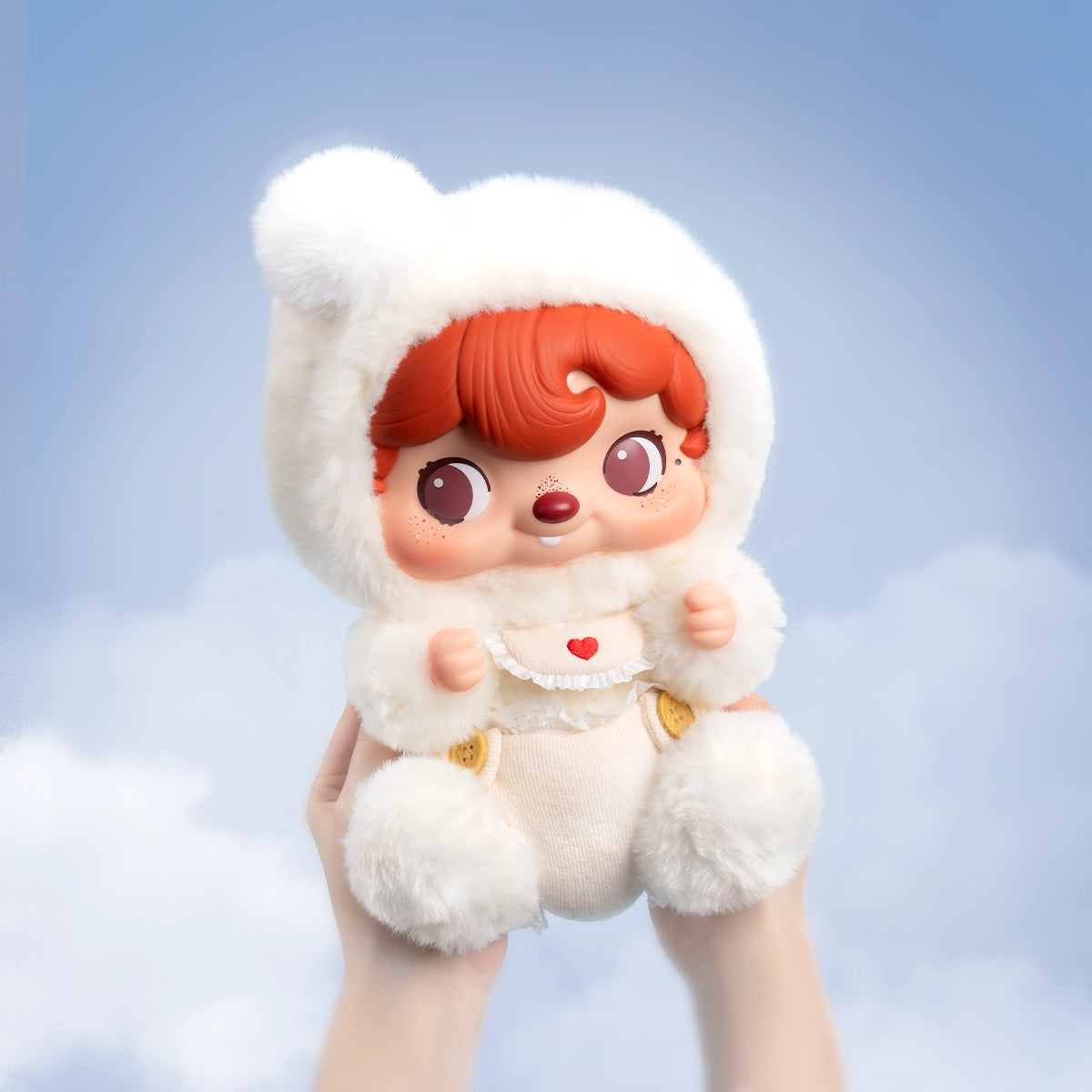 POUKAPOUKA Cloud Baby plush held up against a blue sky, red-haired baby in fluffy white bear-hood bunting