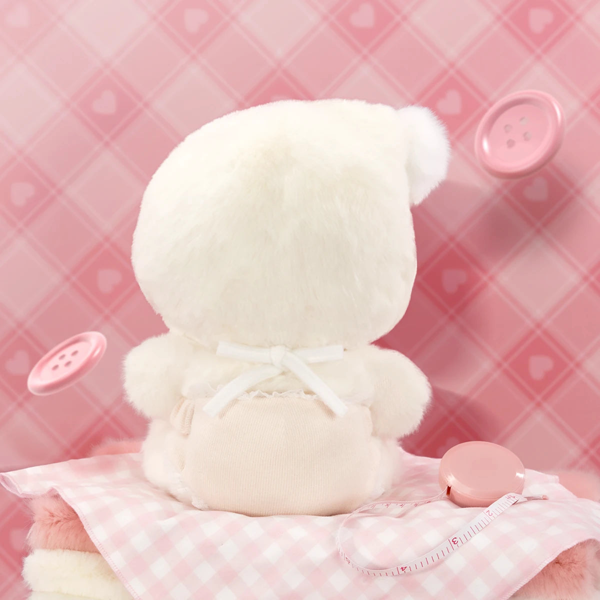 Back view of POUKAPOUKA Cloud Baby plush showing pom-pom hood and ribbon-tied romper